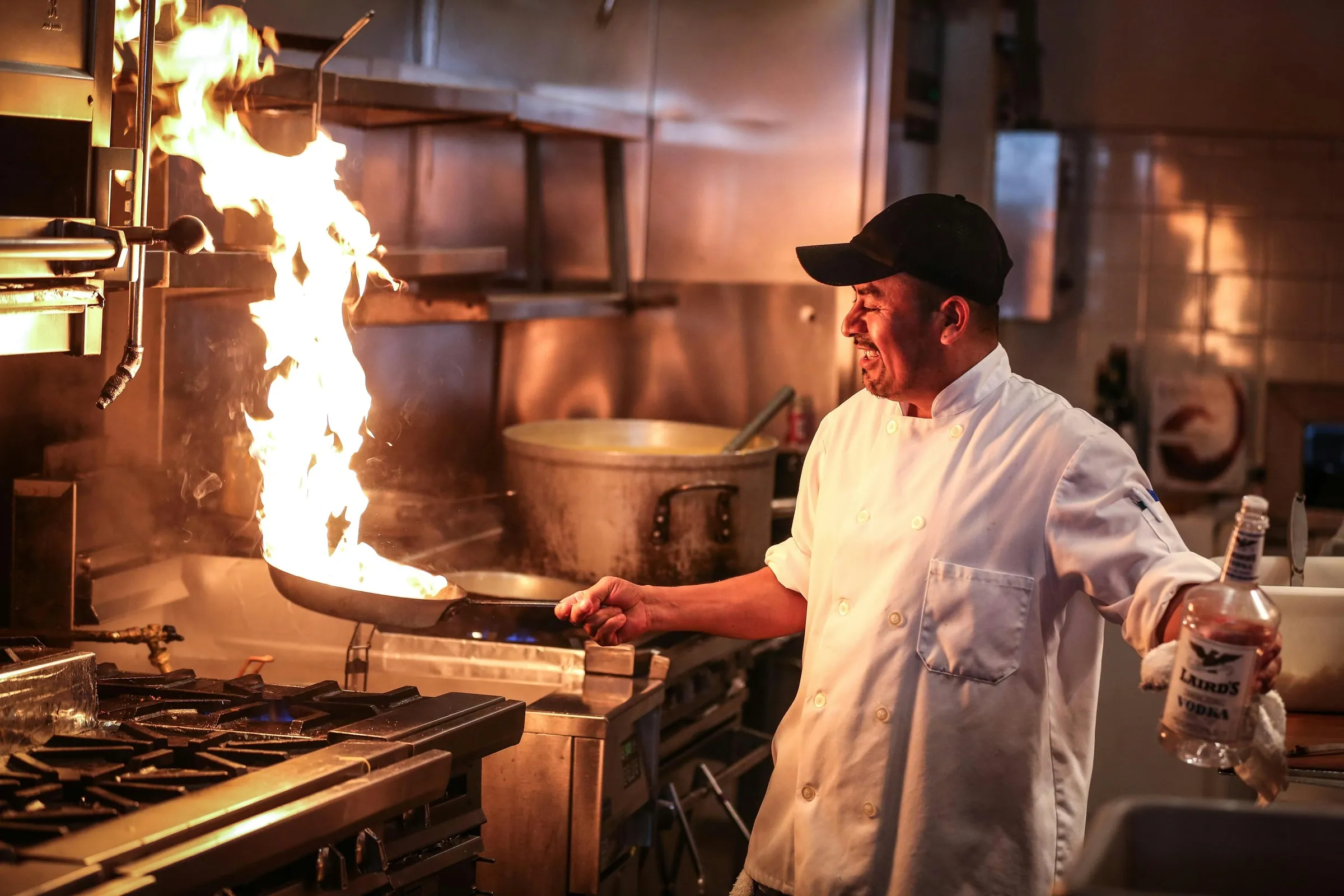 A chef working the flame on a professional kitchen line